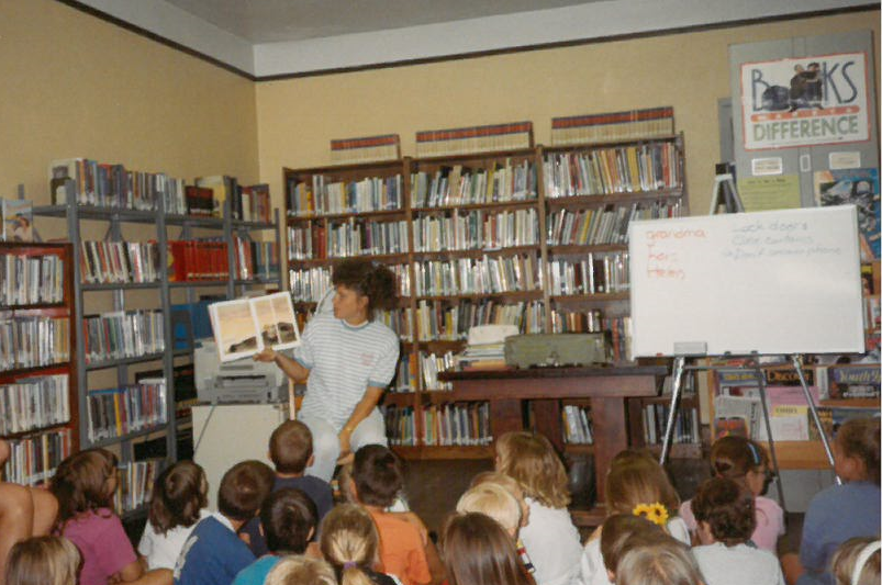woman reading a book to children in a library