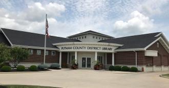 brick building flag and pole bushes Putnam County District Library